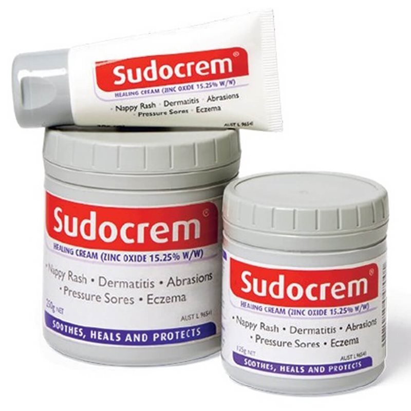 Three Sudocrem containers—two tubs and a tube—show red and white labels stating their use for nappy rash, eczema, dermatitis, abrasions, and pressure sores.