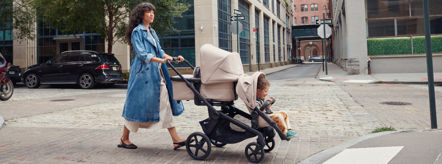 Woman pushing a Bugaboo Kangaroo stroller with a child on a city street