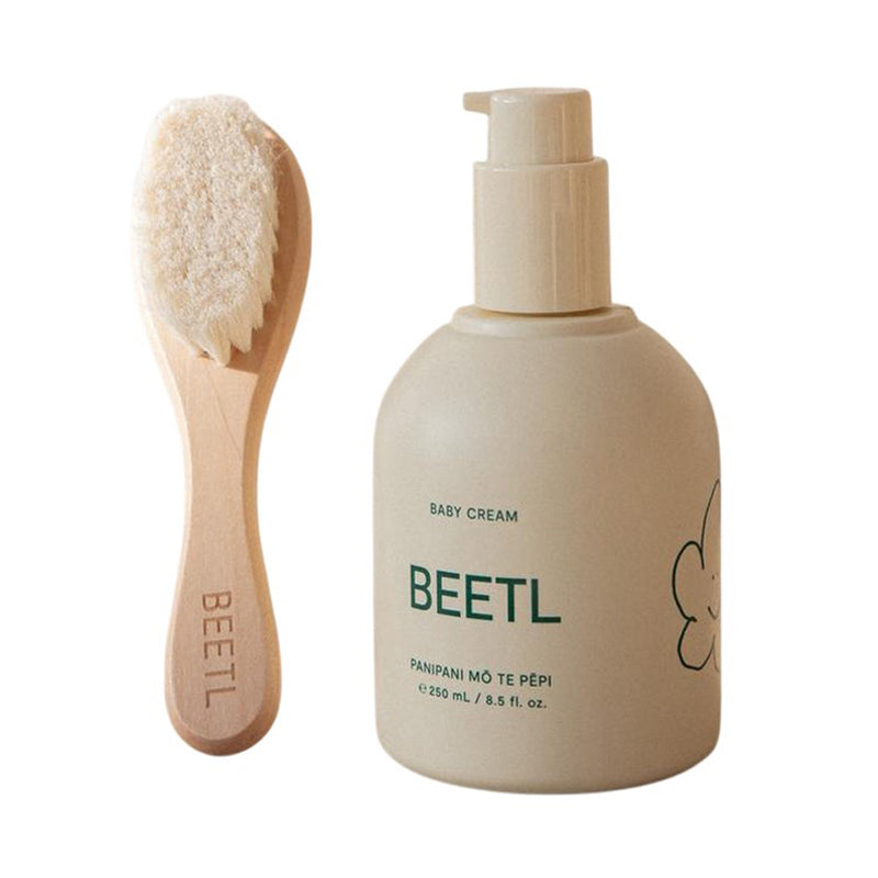 A BEETL Cradle Cap Kit, featuring a natural baby brush with soft bristles and a beige pump bottle of BEETL baby cream, soothes little scalps and helps with cradle cap—perfect for gentle care.