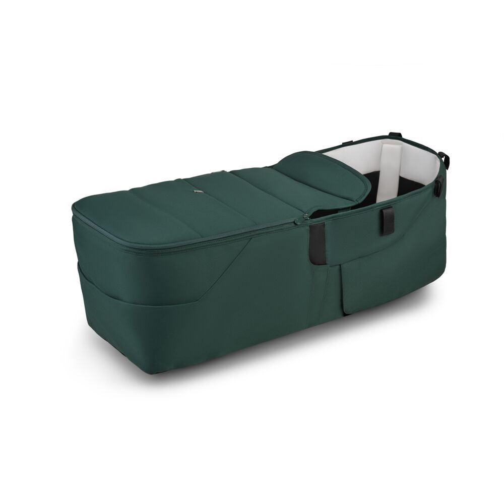 The Bugaboo Donkey 6 Twin Bassinet Fabric Complete by Bugaboo is a dark green portable baby bassinet with black handles, plush fabric, a soft cushioned interior, shown on a white background.