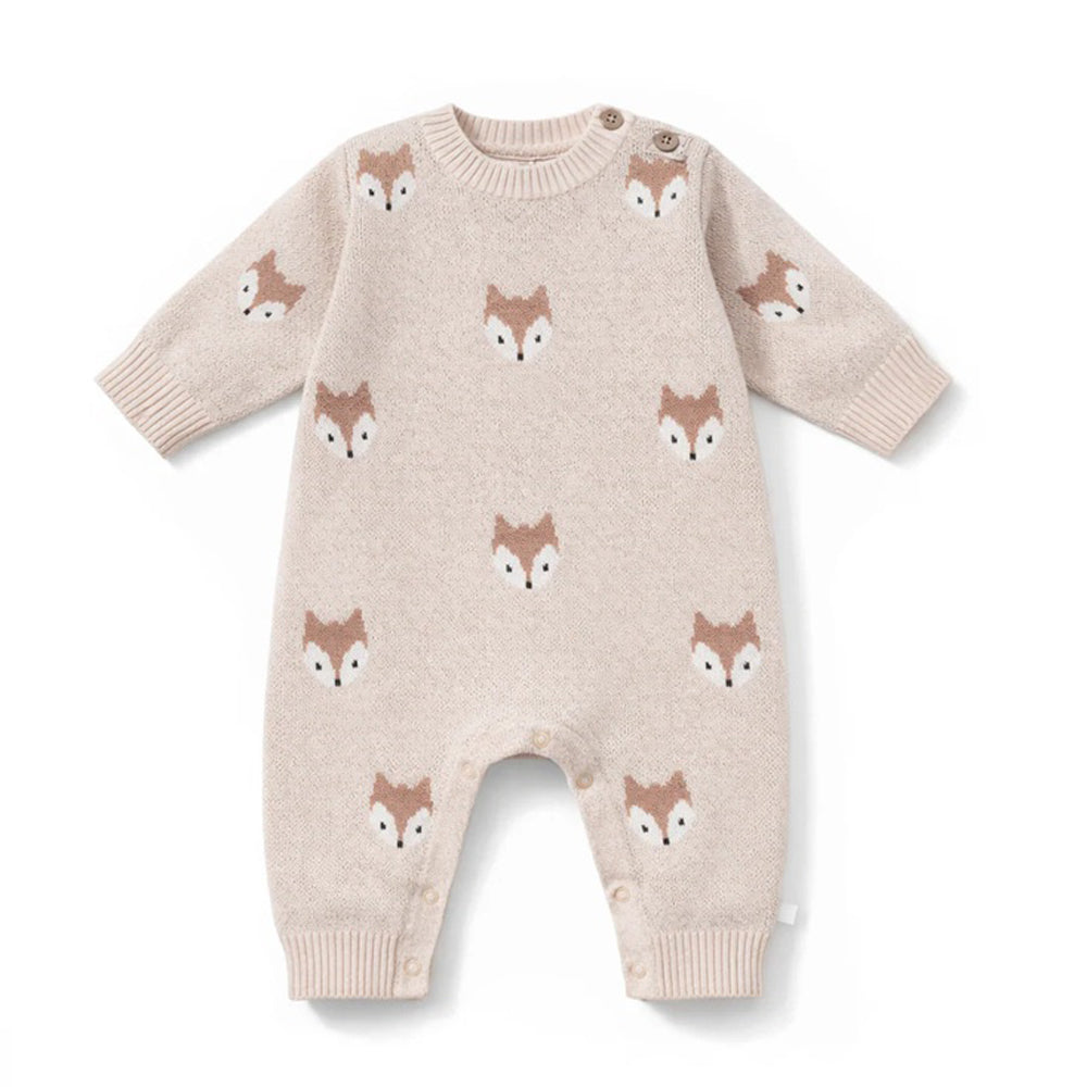 The Aster & Oak Fox Knit Romper in Crystal Grey is a cozy natural cotton romper with long sleeves and legs, featuring brown and white fox faces, plus buttons on one shoulder and the inseam for easy winter changing.