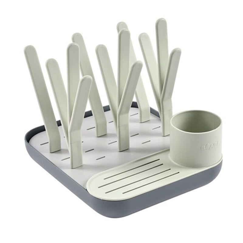 The Beaba Forest Drying Rack by Beaba offers upright prongs for plates and bottles, a slotted draining area, and a round detachable cutlery cup—all in modern light gray and white—for a stylish, hygienic bottle drying solution.