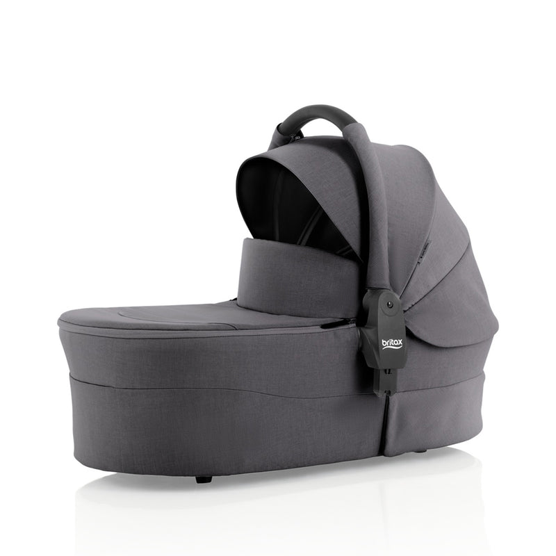 The Britax Safe-n-Sound Aptana Bassinet in gray features a curved UPF 50+ canopy and carrying handle for portability and comfort, providing a safe lie-flat option on a white background.