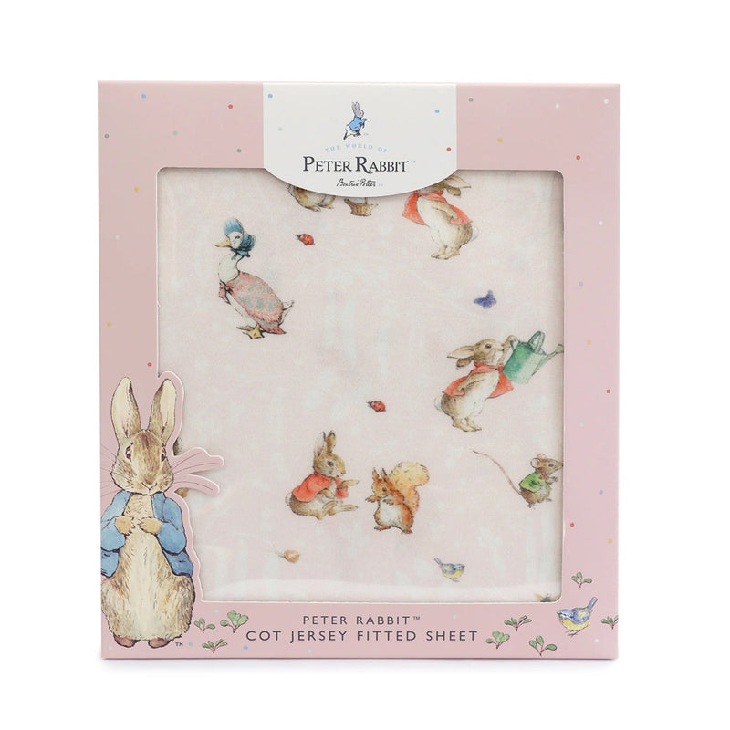 A pink Bubba Blue box displays the Flopsy Mopsy & Cottontail cot fitted sheet, made from soft jersey bamboo cotton and featuring Peter Rabbit and other Beatrix Potter characters. A cutout window reveals the printed sheet inside.