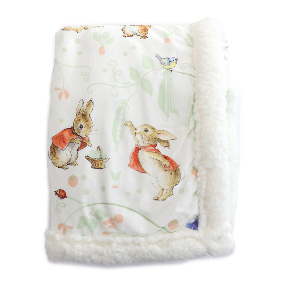 The Bubba Blue Flopsy Mopsy & Cottontail Cuddle Blanket is a soft white nursery blanket with fluffy edges, storybook bunny illustrations, a butterfly, and plants—perfect for little ones.
