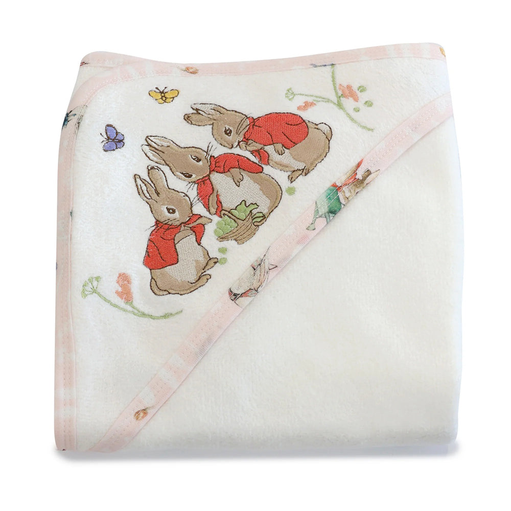 The Bubba Blue Flopsy Mopsy & Cottontail Hooded Towel is a soft white baby towel with a pink border, decorated in one corner with three rabbits in red jackets, butterflies, and flowers.