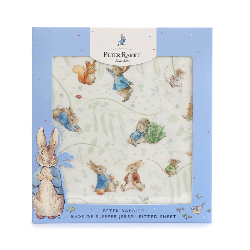 A light blue box displays the Bubba Blue Peter Rabbit & Benjamin Bunny Bedside Sleeper Fitted Sheet, featuring playful animal illustrations on white jersey fabric with elasticized edges and classic Bubba Blue Peter Rabbit branding.