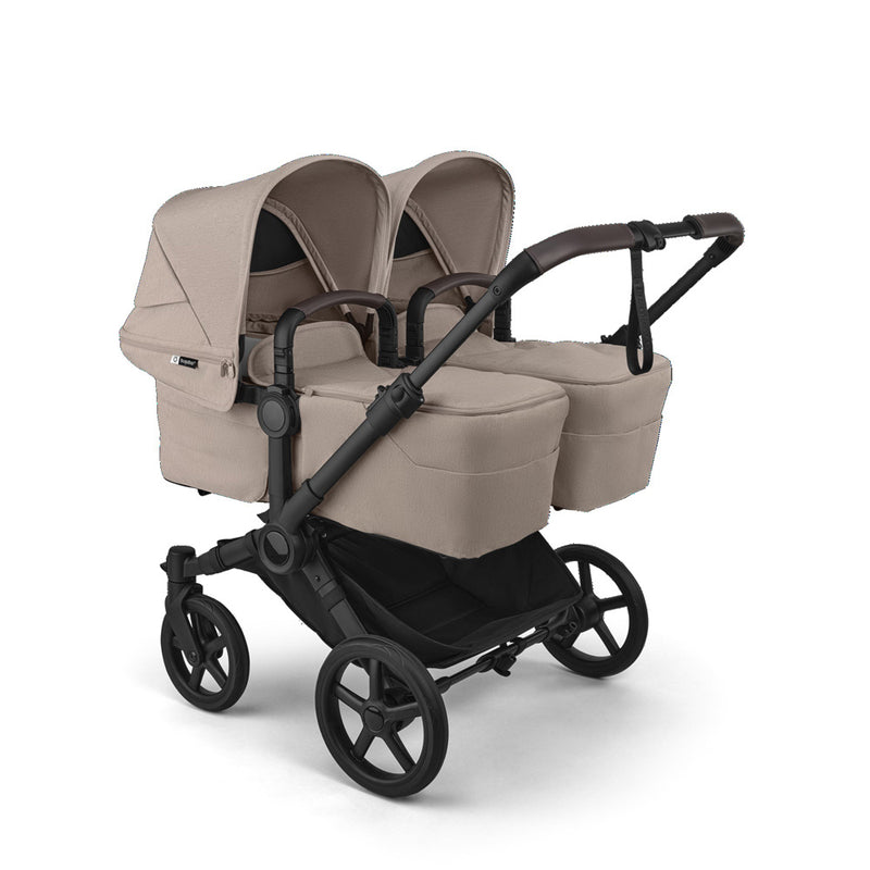 The Bugaboo Donkey 6 2-In-1 Twin Pram by Bugaboo features a beige side-by-side design with two seats, individual canopies, black wheels, a sturdy black frame, and a spacious storage basket—perfect for twins.