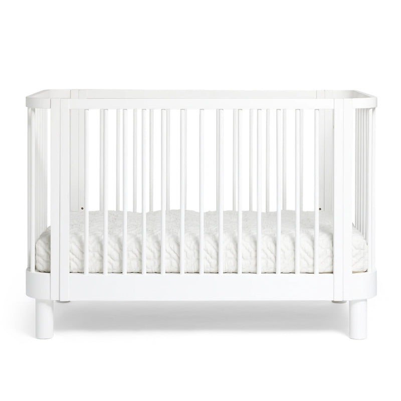 The Cariboo Florence Cot by Cariboo is a modern white New Zealand Pine cot with vertical slats and a white mattress, ideal for nursery furniture, shown against a plain background.