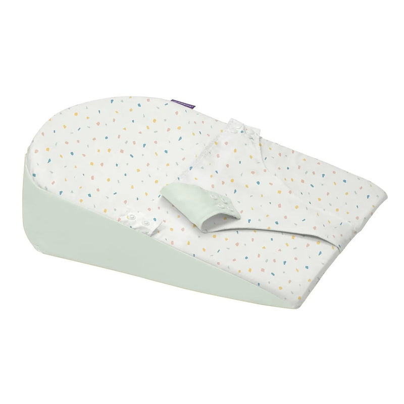 The Clevamama ClevaMama Clevafoam Reflux Wedge Elevated Support is a soft, wedge-shaped baby lounger with a white, dot-patterned cover and secure fabric strap—ideal for added comfort and support for babies with reflux.