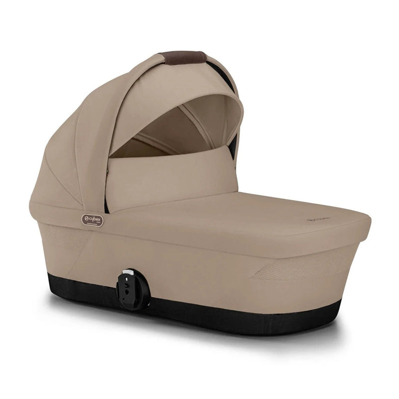 The Cybex Gazelle S Carry Cot by Cybex is a beige infant bassinet with a black base, side latch, UPF50+ sun canopy, and breathable mesh window; it attaches to stroller systems for comfort and convenience.