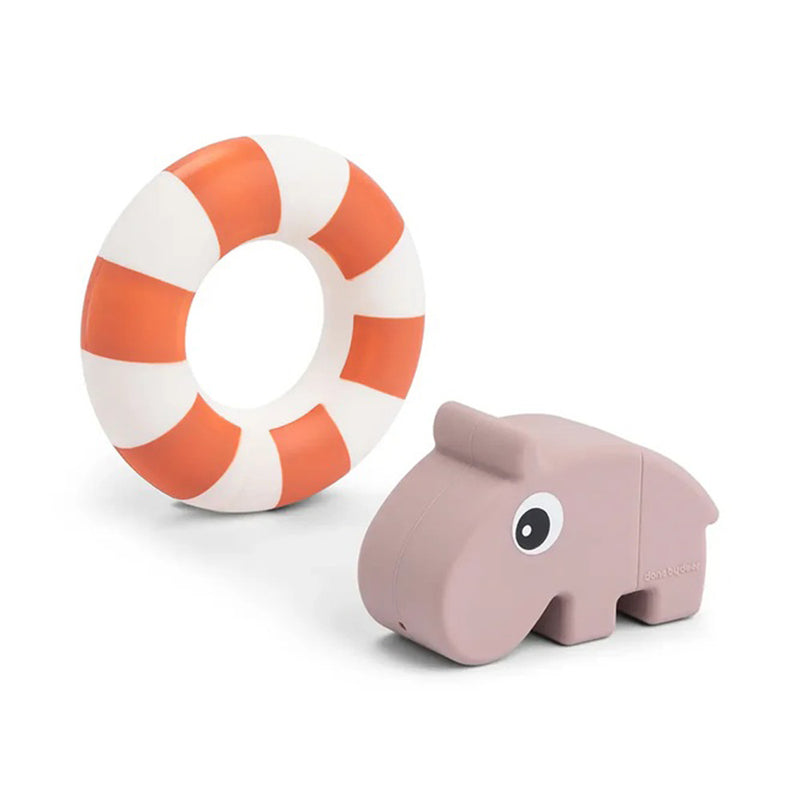 A Done By Deer Bath Squirter Toy Ozzo Powder, a small light purple silicone hippo with a cute cartoon face, sits beside a round orange and white striped lifebuoy on a white background.