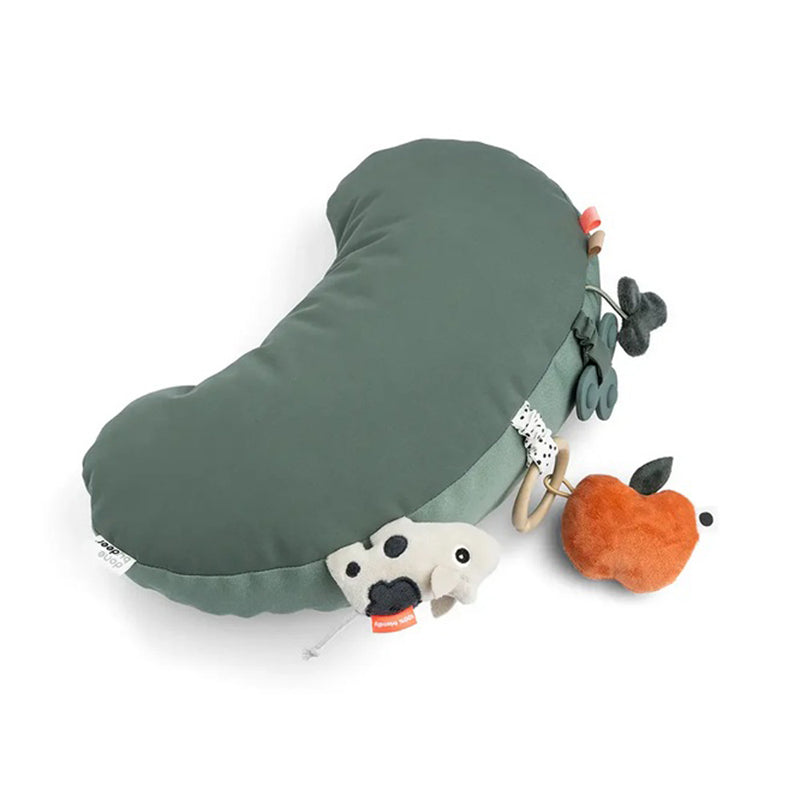 The Done By Deer Tummy Time Activity Toy Tiny Farm Green features a kidney-shaped sensory pillow with attached soft toys—a small cow, leaves, rings, and an orange plush apple—ideal as a teether or tummy time pillow for babies and young children.