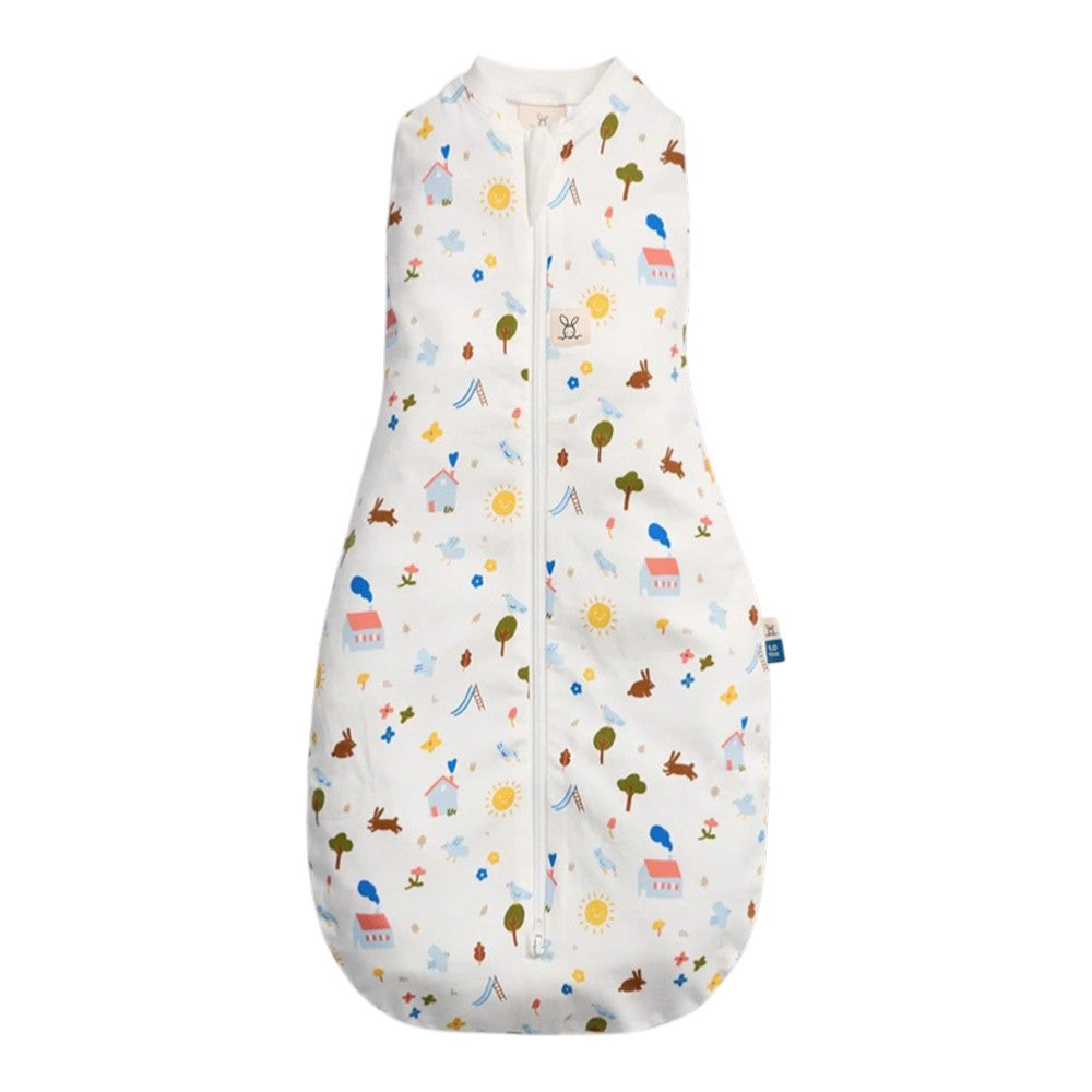 The ErgoPouch 1.0 Tog Cocoon Daydream by ErgoPouch is a sleeveless swaddle sleeping bag with a front zipper, featuring colorful house, tree, sun, cloud, and animal prints on white organic cotton for softness and breathability.