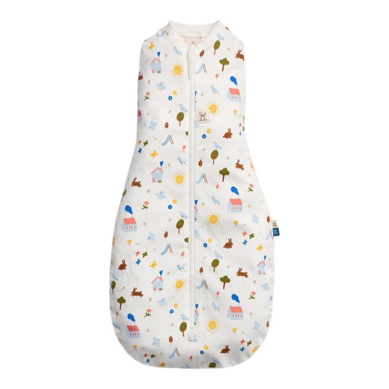 The ErgoPouch 1.0 Tog Cocoon Daydream by ErgoPouch is a sleeveless swaddle sleeping bag with a front zipper, featuring colorful house, tree, sun, cloud, and animal prints on white organic cotton for softness and breathability.