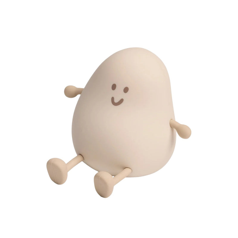 The ErgoPouch Blobby Bedtime Lamp is a small, beige, bean-shaped night light with a smiling face and simple stick arms and legs—perfect for adding charm to any bedtime routine.