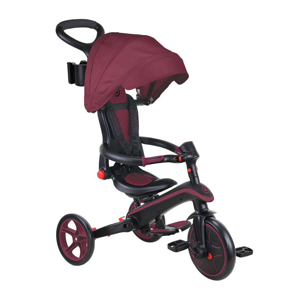 The Globber EXPLORER TRIKE Foldable 4in1 by Globber is a maroon and black tricycle for toddlers featuring a sun canopy, adjustable seat, safety harness, backrest, and rear handle for adult steering.