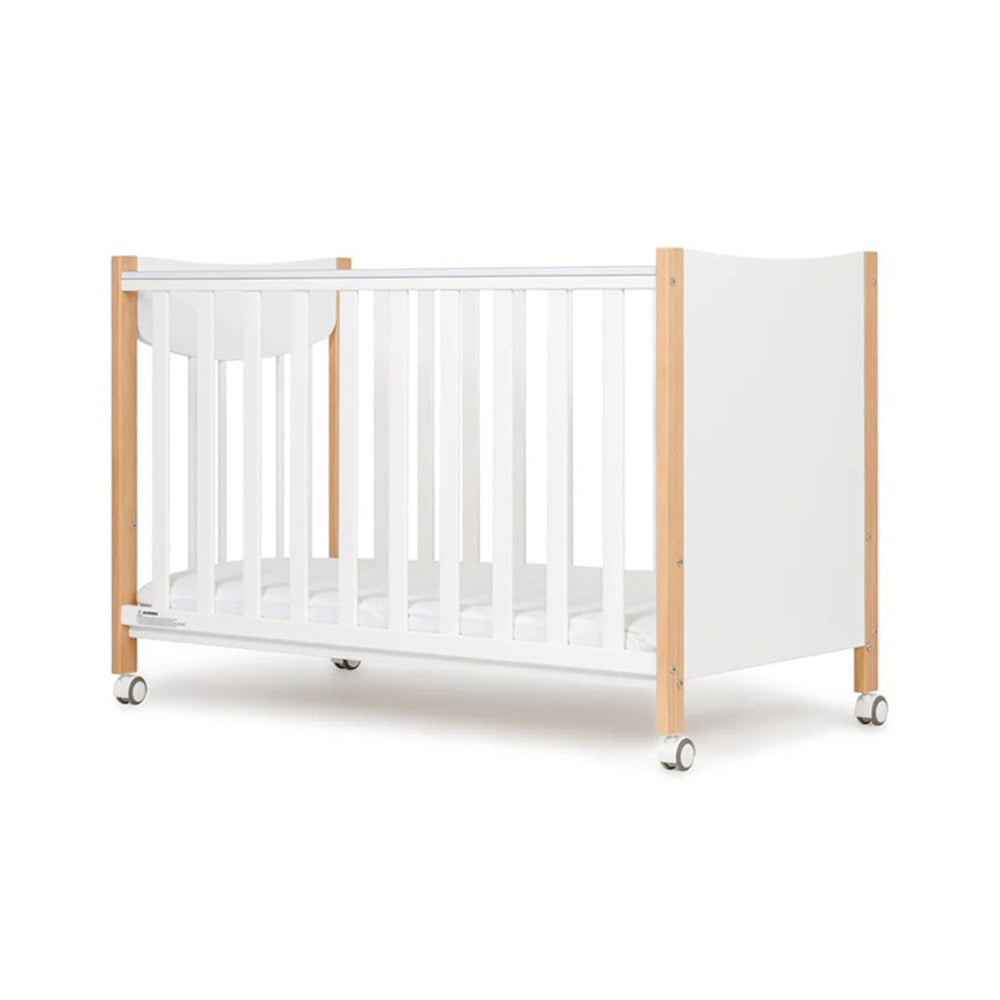 The Grotime Lucas Compact Cot by Grotime features a modern white design with wooden end panels, vertical slats, and four wheels for easy mobility—ideal for small spaces. Shown on a plain white background.