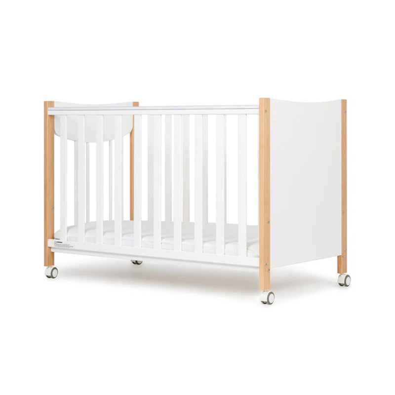 The Grotime Lucas Compact Cot by Grotime features a modern white design with wooden end panels, vertical slats, and four wheels for easy mobility—ideal for small spaces. Shown on a plain white background.