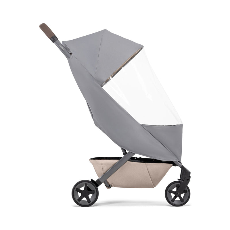 A side-profile of a modern grey baby stroller with the Joolz Aer2 Raincover by Joolz and a beige storage basket underneath, displayed on a white background for excellent stroller weather protection.