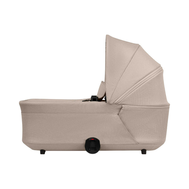 The Joolz Hub2 Bassinet by Joolz is a beige baby bassinet with a canopy, shown from the side on a white background. Suitable for overnight sleep, it features a breathable mattress, small black latch, and sturdy feet.