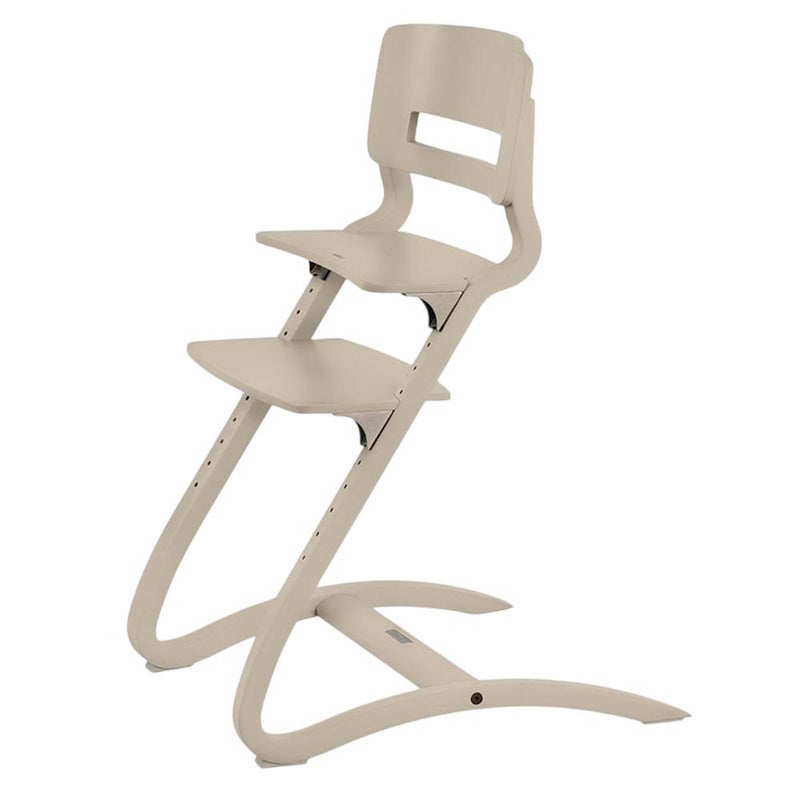The Leander Louie Chair by Leander is an ergonomic, minimalist dining chair for children, featuring a beige finish, curved legs, cut-out backrest, and adjustable seat and footrest heights with multiple adjustment holes.