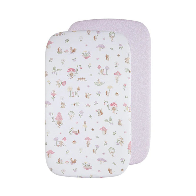 The Living Textiles Bedside Sleeper Fitted Sheet 2pk Whimsical Wonderland includes two organic cotton fitted sheets: one with a pastel animal, mushroom, and plant design, and one solid light pink with a subtle floral pattern. Both feature rounded corners.