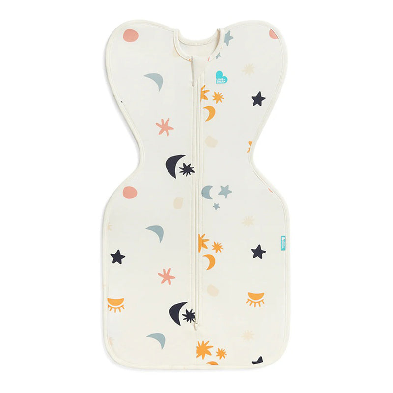 The Love To Dream Swaddle Up 1.0T Organic Stretch Cotton Lunar Buff is a cream baby swaddle with a center zipper for arms up self-soothing, featuring stars, moons, suns, and abstract shapes in orange, peach, blue, and black.
