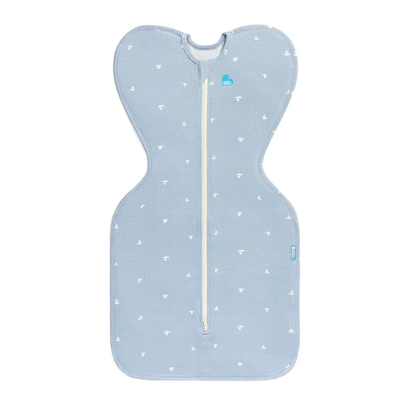 The Love To Dream Swaddle Up 1.0T Viscose From Bamboo Boats Mist Blue is a mist blue, bamboo baby swaddle by Love To Dream with white boat patterns, a central white zipper, and an Arms Up design for comfortable swaddling.