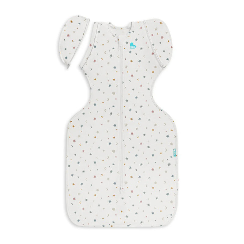 The Love To Dream Swaddle Up Transition Bag 0.2T Stretch Organic Cotton in Starlight White features a hip-healthy design, zip-off wings, front zipper, and a small multicolored star pattern.