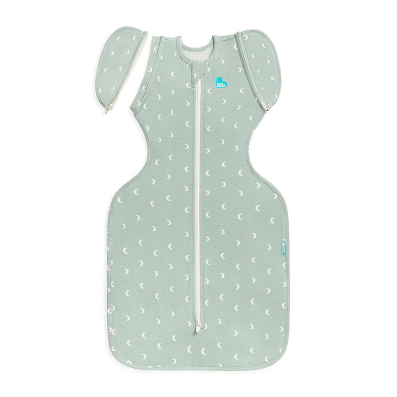 The Love To Dream Swaddle Up Transition Bag 1.0T Stretch Cotton Moon Olive is a green baby sleep sack with white crescent moons, detachable wing-like sleeves, and a central zipper—designed for hip-healthy, restful sleep.