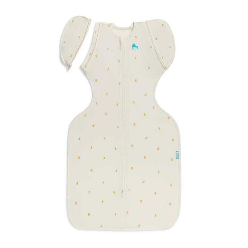 The Love To Dream Swaddle Up Transition Bag 1.0T Viscose From Bamboo Lemons Cream is a sleeveless, cream-colored swaddle bag with small yellow lemon prints, removable wings for transition, and a center front zipper.