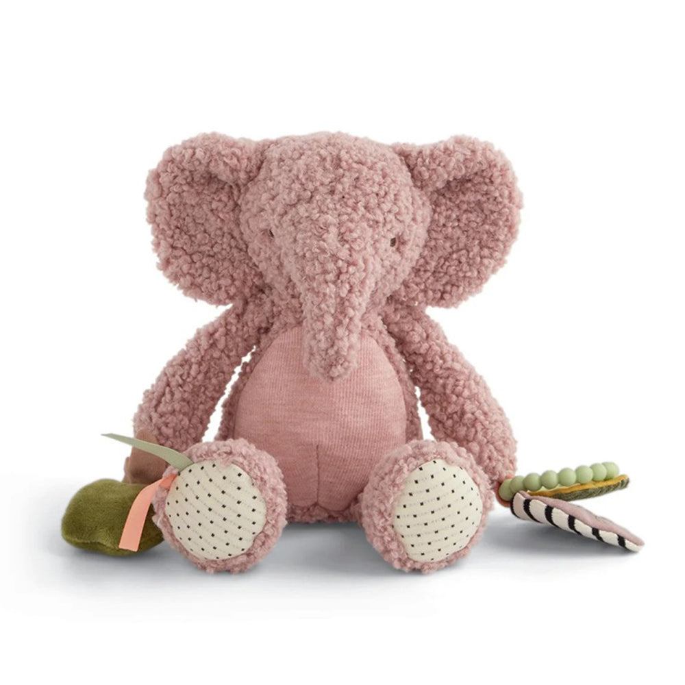 The Mamas & Papas Activity Toy Edie Elephant is a pink, fuzzy soft toy with big ears and spotted feet. It sits upright and comes with green leaf and striped accessories—an ideal baby cuddle toy from Mamas & Papas, shown on a white background.