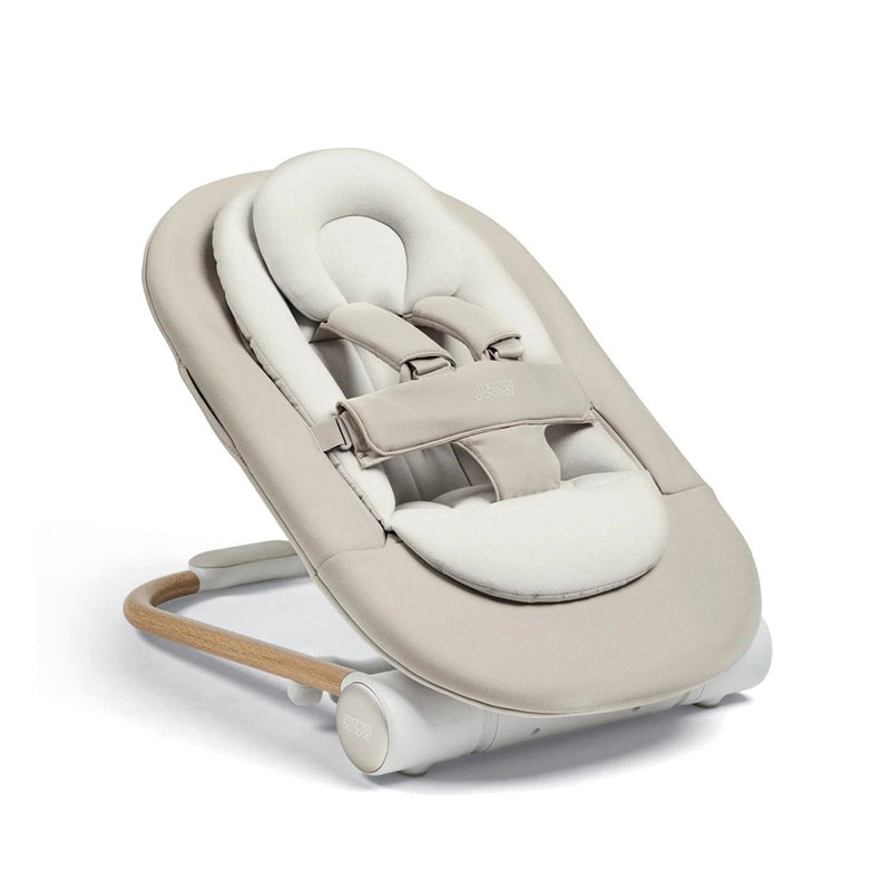 The Mamas & Papas Eno Bouncer by Mamas & Papas features a beige padded seat, adjustable harness, soft head support, and a wooden base for comfort and safety.