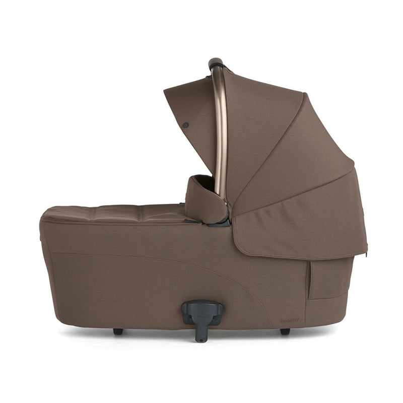 The Mamas & Papas Ocarro2 Bassinet in brown, shown from the side with its canopy extended and a visible black attachment at the base, is designed for overnight sleep with a lie-flat mattress.
