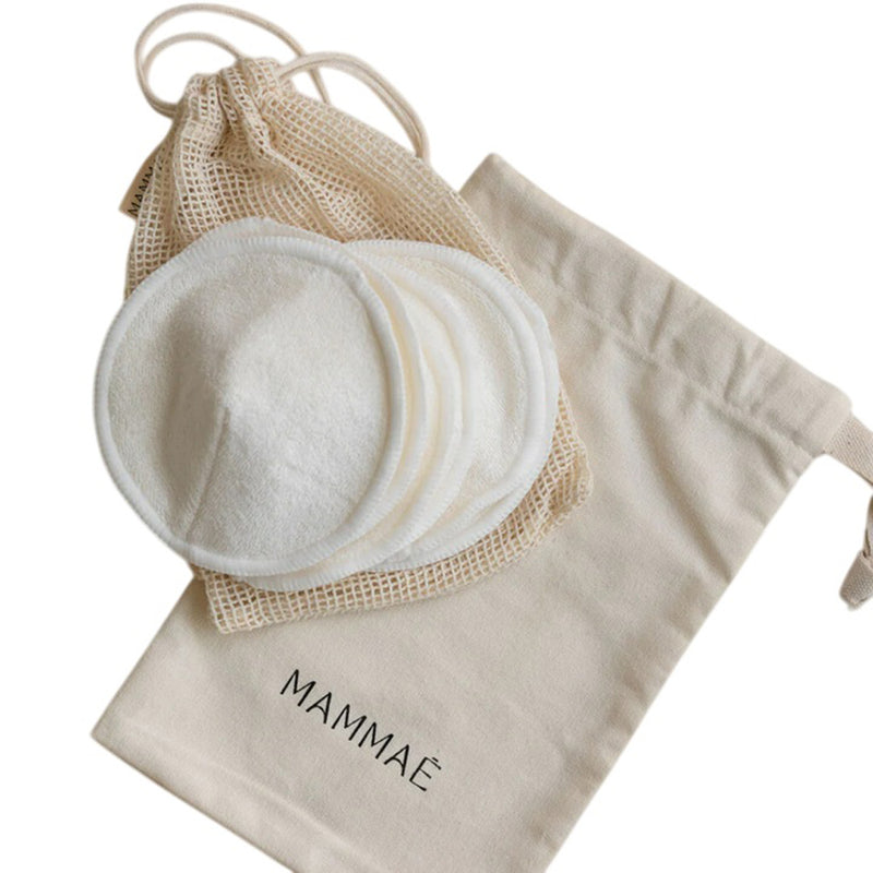 Mammae Bosom Reusable Organic Contoured Breast Pads by Mammae are arranged neatly on a white background with a beige mesh bag and a drawstring pouch labeled "MAMMAE." These hypoallergenic pads and accessories offer comfort and sustainability.