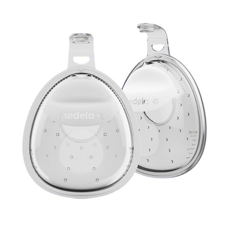 The Medela In-Bra Breast Milk Collector includes two clear, oval shells with small ventilation holes, measurement markings, and attached hooks for secure placement.