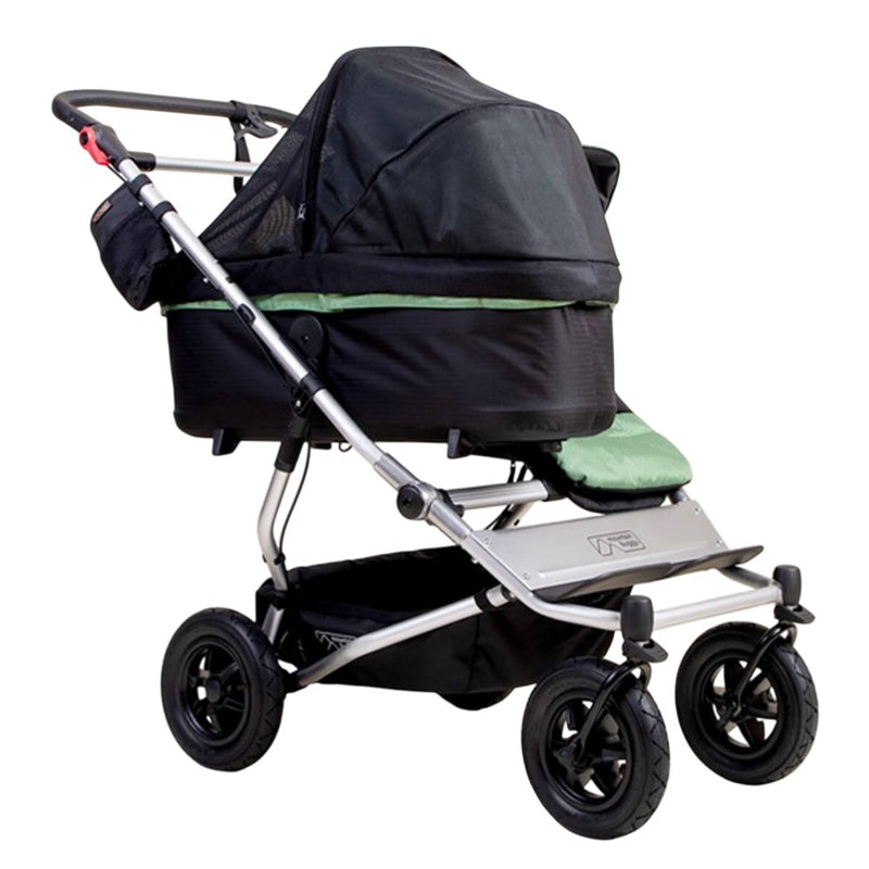 The Mountain Buggy Carrycot Plus Sun UV Mesh & Blackout Cover Set for V4 Duet, shown from the side against a white background, features a mesh cover for airflow and sun protection. Brand: Mountain Buggy.