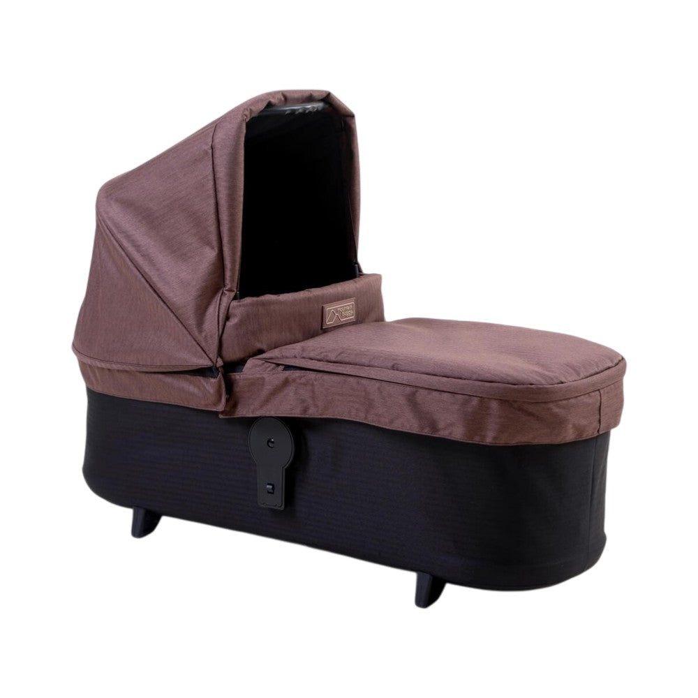 The Mountain Buggy Carrycot Plus for Duet V4 by Mountain Buggy is a brown and black portable newborn bassinet with a canopy cover, designed for lie-flat comfort. It is pictured on a white background.