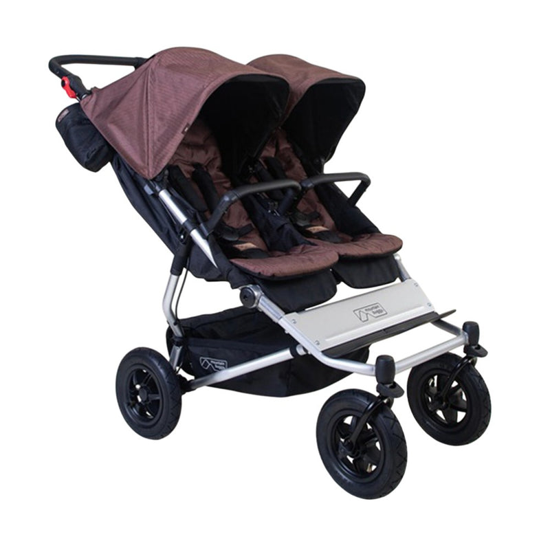 The Mountain Buggy Duet V4 by Mountain Buggy is a brown side-by-side stroller with two seats, black harnesses, large wheels, and individual sun canopies—ideal for comfortably transporting two children together on all terrains.