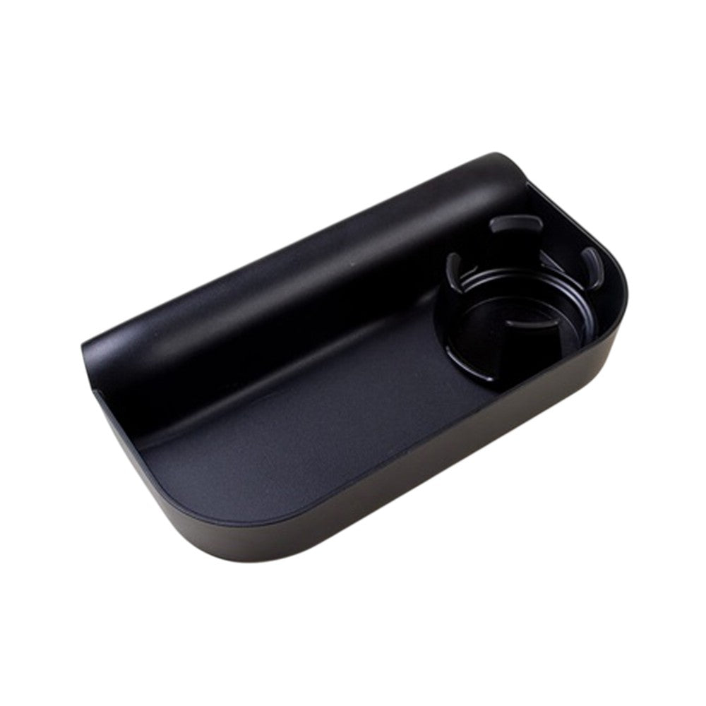 The Mountain Buggy Food Tray by Mountain Buggy is a black plastic car organizer with a rectangular tray and circular cup holder with dividers on the right, designed to fit between car seats—perfect as a buggy food tray.