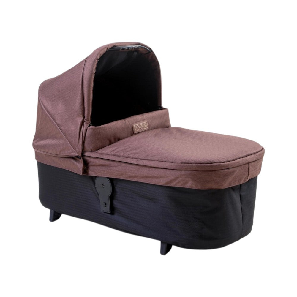 The Mountain Buggy Carrycot Plus for Urban Jungle V4, by Mountain Buggy, is a brown and black bassinet with canopy. Its soft exterior and short legs make it portable and comfy as a newborn carrycot or a modular toddler seat as your child grows.