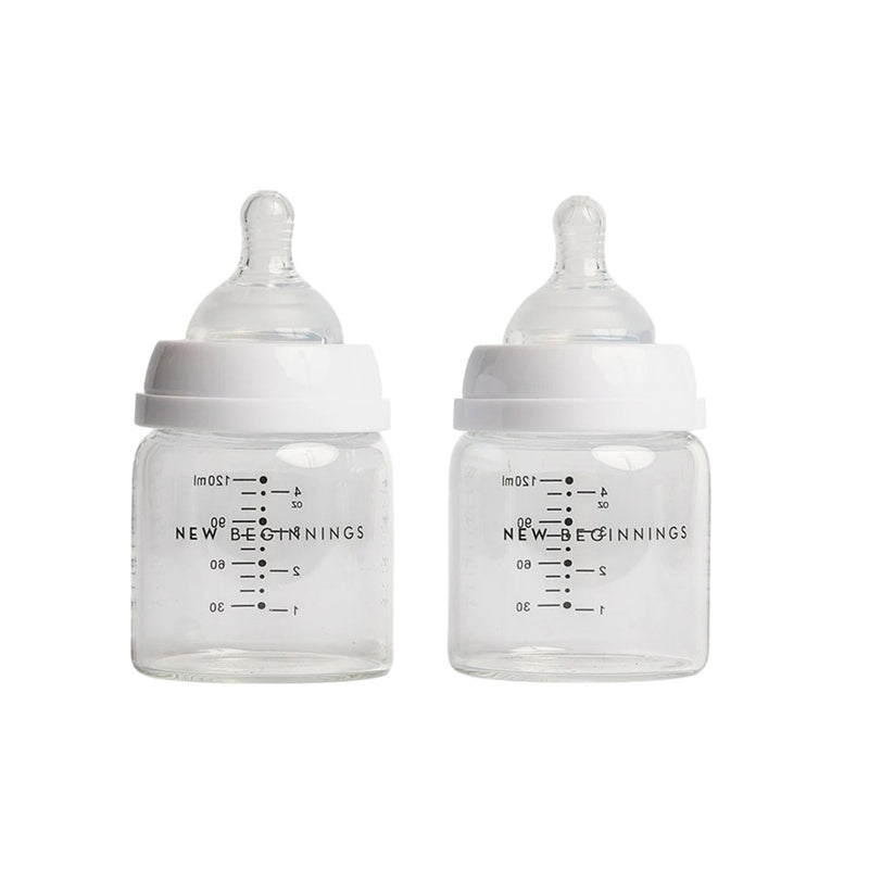 The New Beginnings Classic Glass Bottle 120ml Twin Pack features two clear glass baby bottles with white lids, silicone nipples, measurement markings, and "NEW BEGINNINGS" printed on the front.