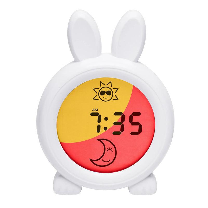 The Oricom Sleep Trainer Clock by Oricom is a white bunny-shaped clock with big ears and feet. Its backlit screen shows “7:35 AM” in black, plus yellow sun and red moon icons—ideal for helping toddlers follow their sleep routines.