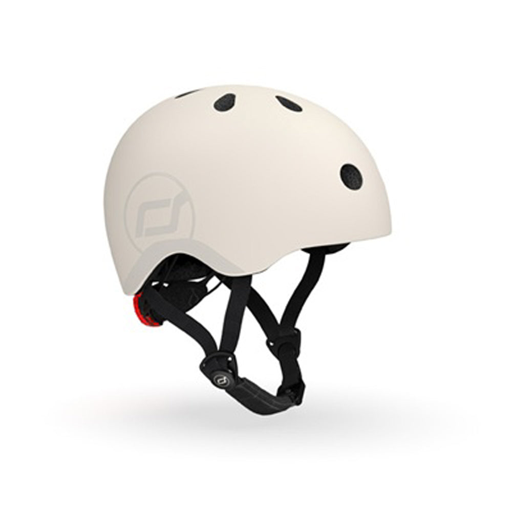 The Scoot and Ride Helmet (S-M) by Scoot and Ride is a matte white skate-style kids' helmet with black ventilation holes, adjustable black straps, a side logo, and an integrated LED light, shown on a plain white background.