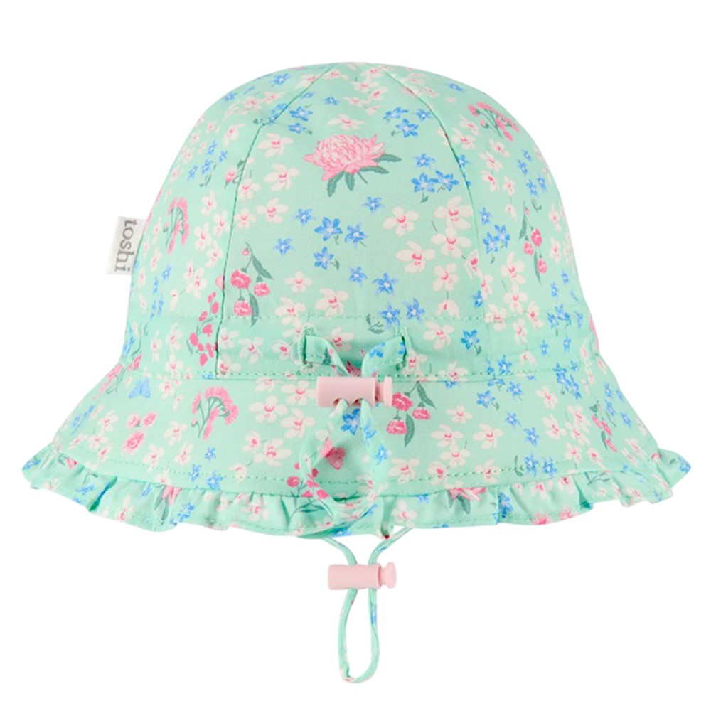 The Toshi Bell Hat Matilda Acacia Mint by Toshi is a light blue baby sunhat with a pink and blue floral pattern, ruffled brim, adjustable chin strap with pink toggles, and offers UPF 50+ UV protection for sunny days.