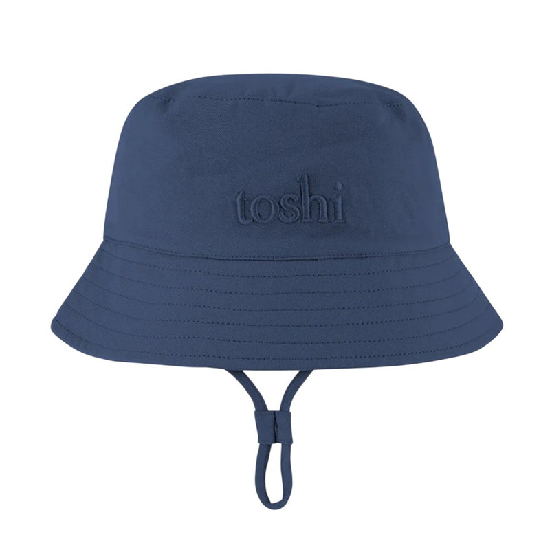 The Toshi Bucket Hat Billy Midnight is a kids' navy cotton hat with "toshi" embroidered on the front, an adjustable chin strap, and UPF 50+ for safe, stylish outdoor adventures.