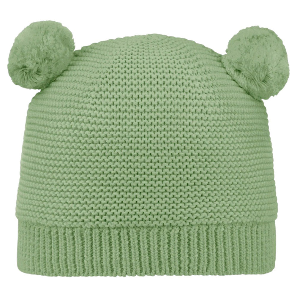 The Toshi Organic Beanie Snowy Gumtree is a light green organic cotton beanie with two fluffy pom-poms resembling bear ears, shown against a white background.