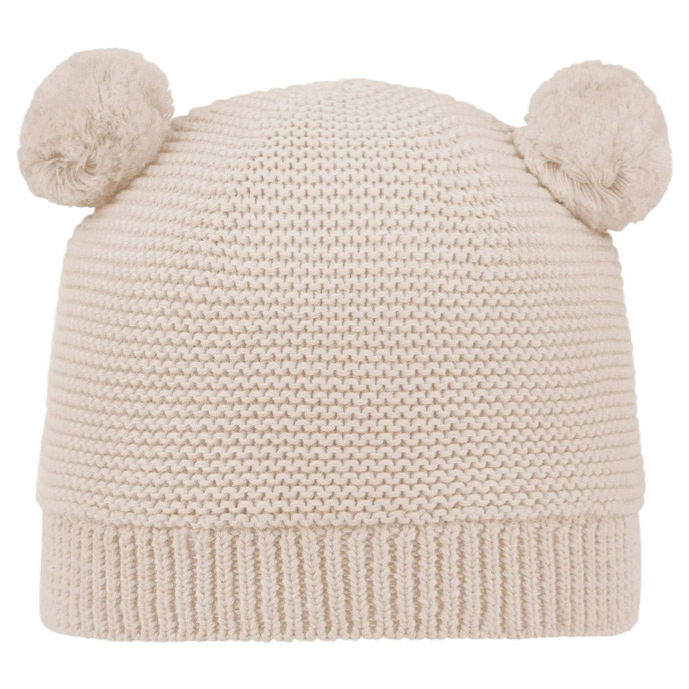 The Toshi Organic Beanie Snowy Oatmeal is a cream-colored organic cotton baby beanie with two fluffy pom-poms resembling bear ears—cute and cozy, perfect for kids.