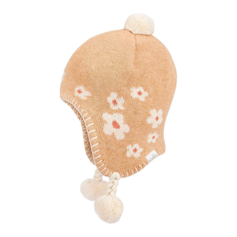 A tan knit baby winter hat featuring white and pink flower patterns, ear flaps, braided ties, and three cream pom-poms—styled like the Toshi Organic Earmuff Mystical Jasmine by Toshi.